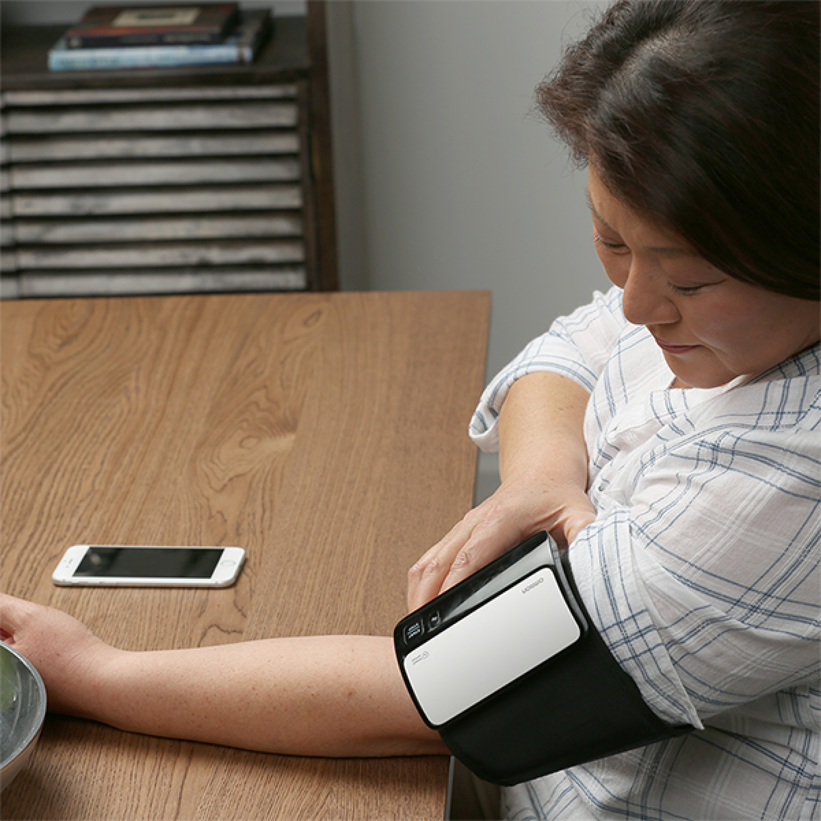 Woman taking blood pressure monitor at home