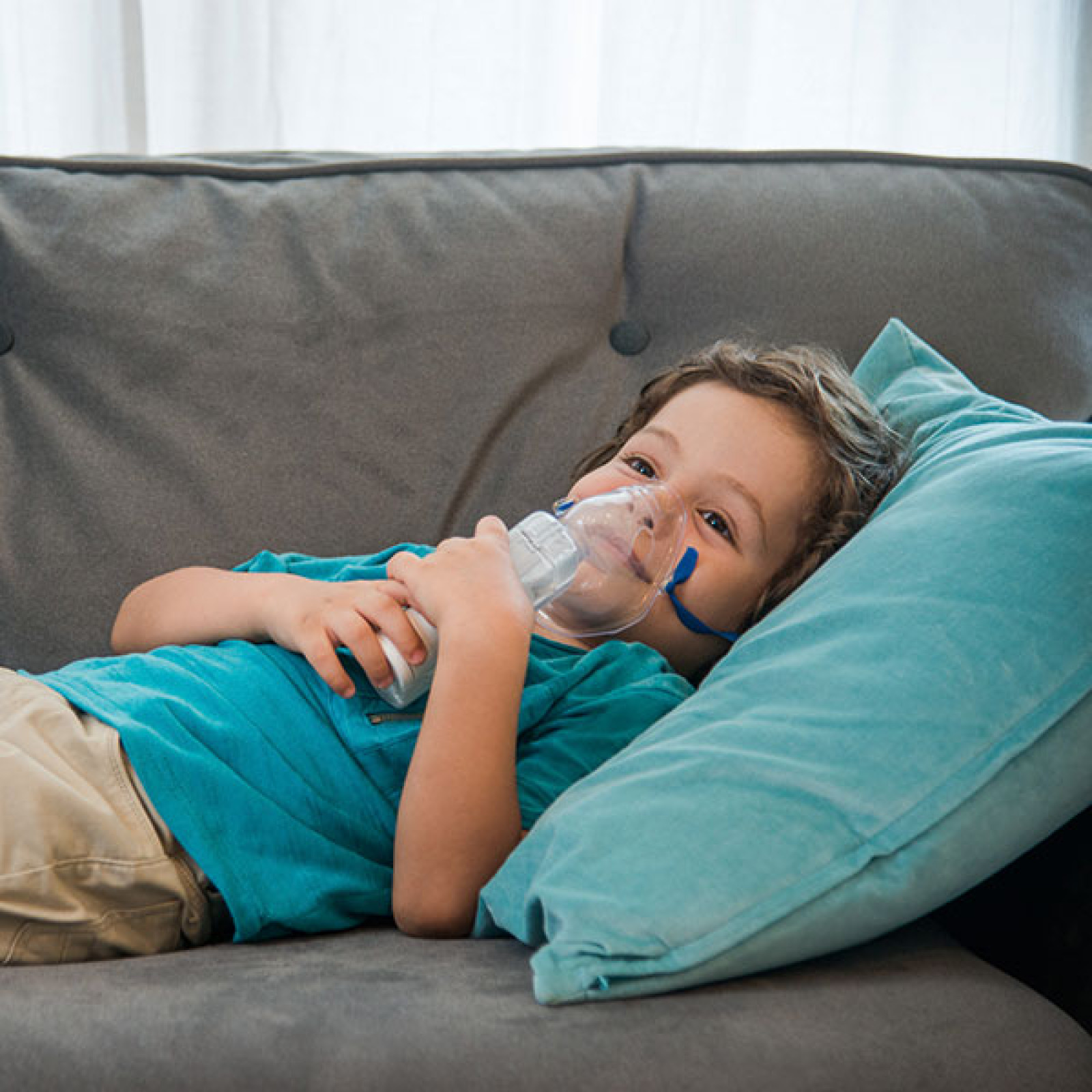 Child taking nebulizer treatment on couch