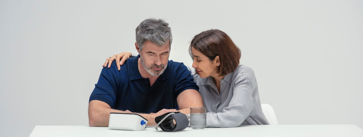 Man and wife at table with blood pressure monitor