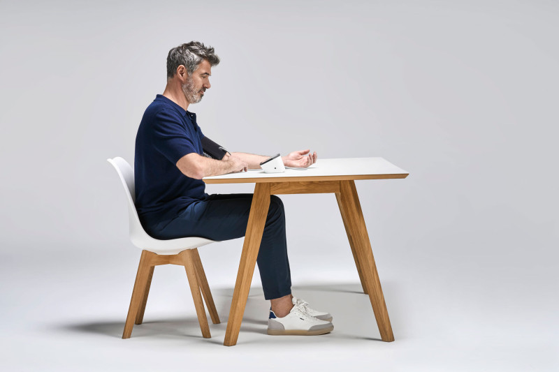 Man taking blood pressure from side at desk