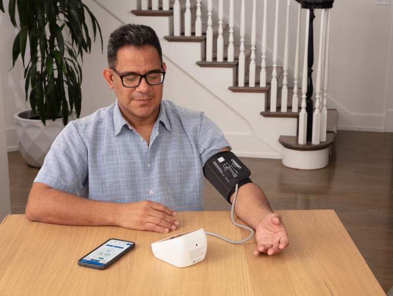 Man taking blood pressure monitor at home