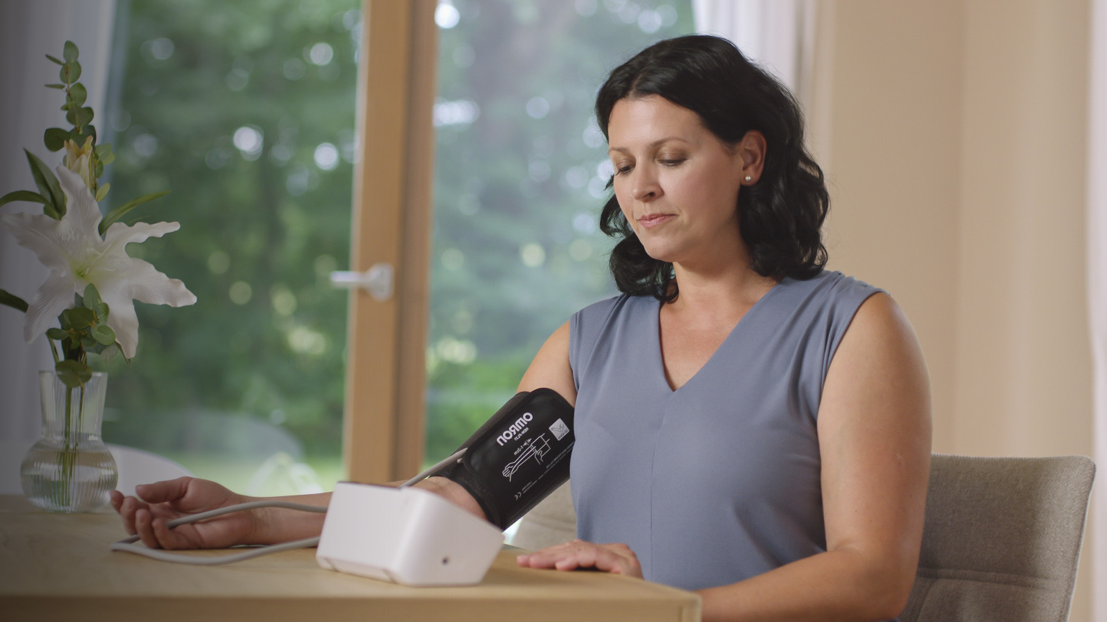 Woman taking blood pressure monitor at home